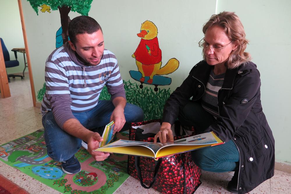 Sari-Johanna Kuittilo ja Mu'taz Awad selaavat lasten kirjaa Lähi-Idän pakolaisleirillä