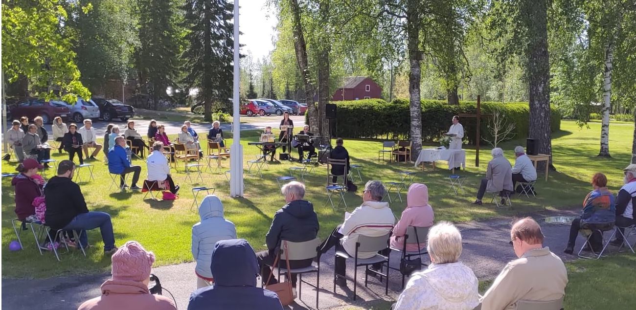 Ihmisiä ulkoilmajumalanpalveluksessa Kalannin seurakuntakodin nurmikolla